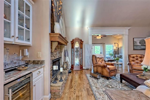 502 Cottage Crest Dr, Clarkesville, GA 30523 - living room with beverage cooler, a ceiling fan, light wood finished floors, a stone fireplace, and a dry bar