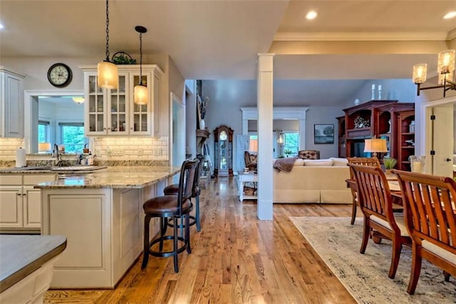 502 Cottage Crest Dr, Clarkesville, GA 30523 - kitchen featuring glass insert cabinets, healthy amount of natural light, a breakfast bar, light wood-style flooring, and ornamental molding
