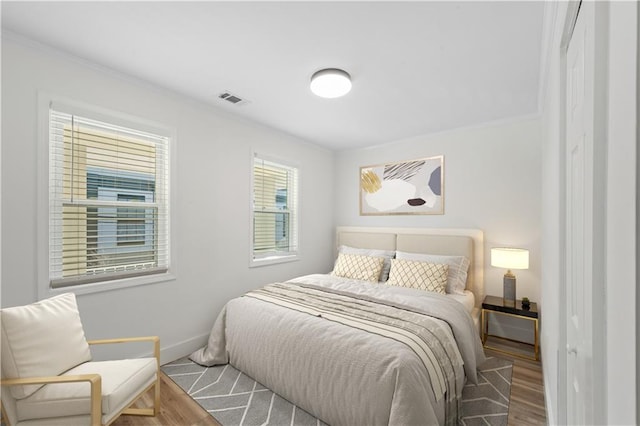 bedroom with ornamental molding and hardwood / wood-style flooring