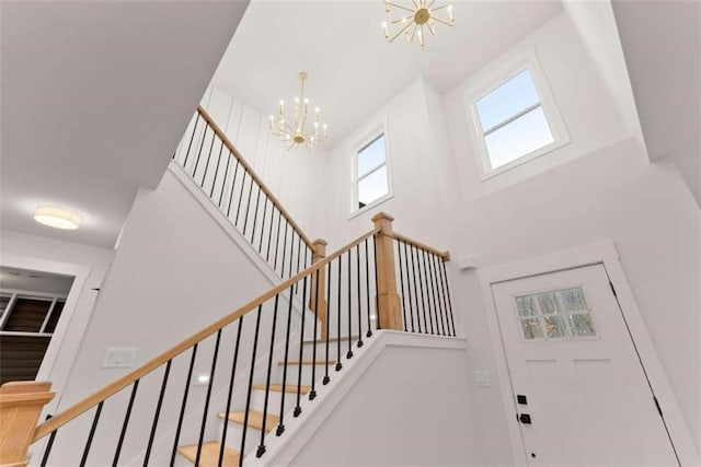 stairway featuring a notable chandelier and a high ceiling