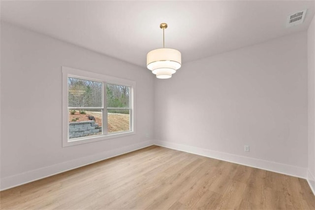 empty room featuring light wood-style floors, baseboards, and visible vents