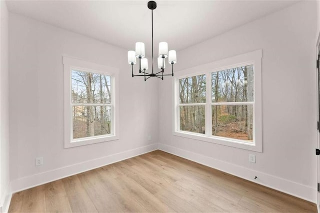 unfurnished dining area with light wood finished floors, baseboards, and a chandelier