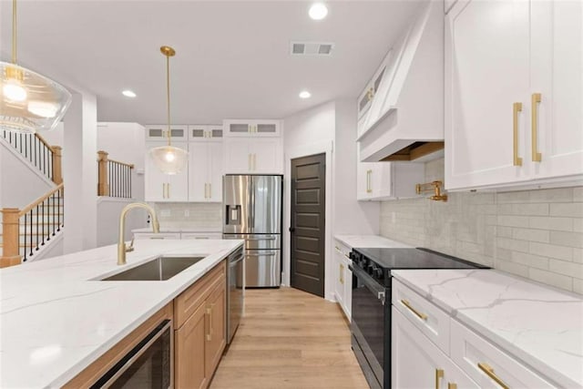 kitchen with visible vents, glass insert cabinets, stainless steel appliances, light wood-style floors, and a sink