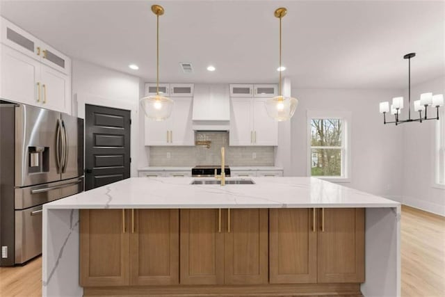 kitchen featuring a sink, white cabinetry, stainless steel fridge with ice dispenser, a large island, and decorative backsplash