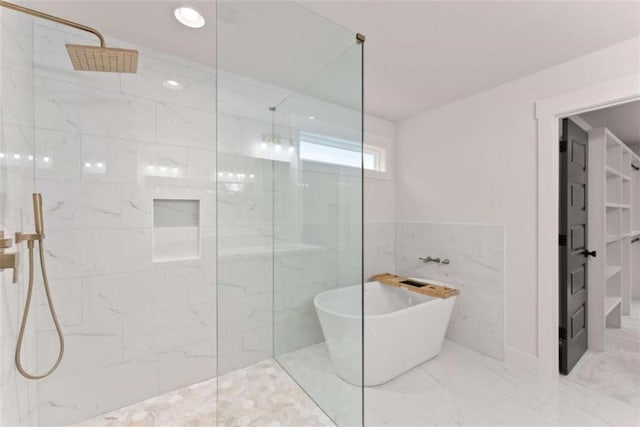 bathroom with marble finish floor, a freestanding tub, tile walls, and a marble finish shower