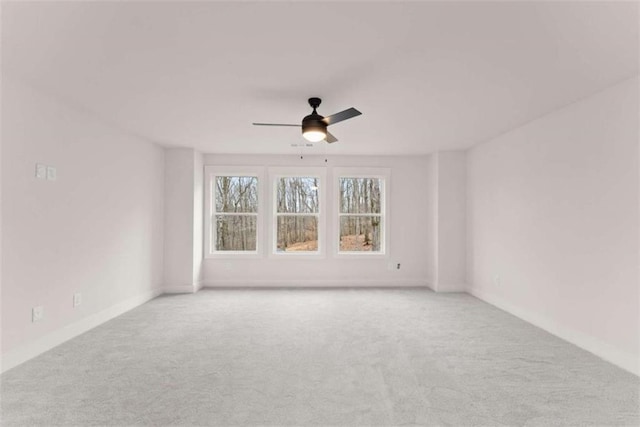 carpeted spare room featuring baseboards and a ceiling fan