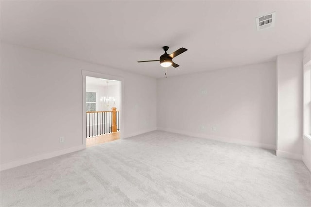 spare room with ceiling fan with notable chandelier, carpet flooring, visible vents, and baseboards