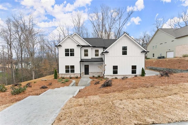 modern farmhouse style home featuring roof with shingles, board and batten siding, and stone siding