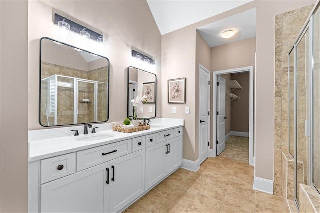 5765 Riley Rd, Cumming, GA 30028 - bathroom featuring a shower stall, a walk in closet, double vanity, lofted ceiling, and baseboards