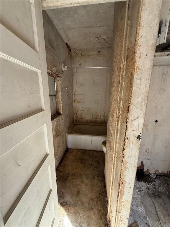 bathroom with toilet and concrete flooring