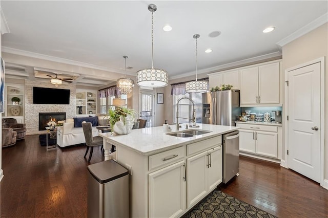 kitchen featuring dark wood-type flooring, ornamental molding, a sink, appliances with stainless steel finishes, and a fireplace