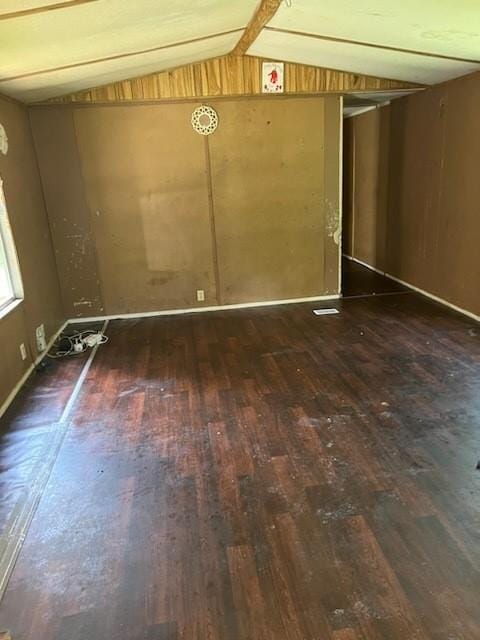 empty room with vaulted ceiling and hardwood / wood-style floors