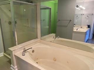 bathroom with a shower stall, a tub with jets, and vanity