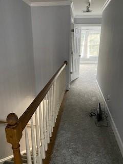 hallway with baseboards, carpet flooring, crown molding, and an upstairs landing