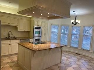 kitchen featuring a center island, double oven, a sink, a chandelier, and black electric cooktop