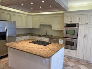 kitchen featuring a tray ceiling, recessed lighting, appliances with stainless steel finishes, a kitchen island, and a sink