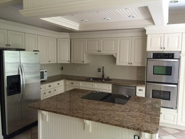 kitchen featuring stainless steel appliances, light tile patterned flooring, a sink, and dark stone countertops