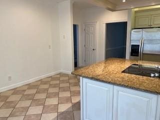 kitchen with stainless steel fridge, black electric stovetop, light stone counters, and baseboards