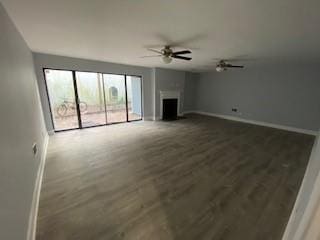 unfurnished living room with a fireplace, baseboards, a ceiling fan, and wood finished floors