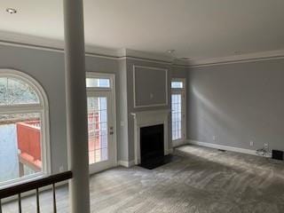 unfurnished living room featuring carpet, a fireplace, baseboards, and crown molding