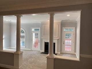 unfurnished living room featuring a fireplace, decorative columns, and crown molding