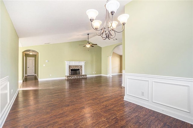 unfurnished living room featuring dark hardwood / wood-style flooring, ceiling fan with notable chandelier, vaulted ceiling, and a brick fireplace