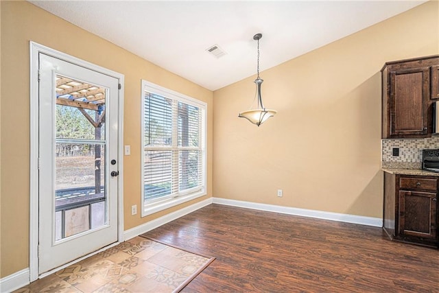 unfurnished dining area with dark wood-type flooring and vaulted ceiling