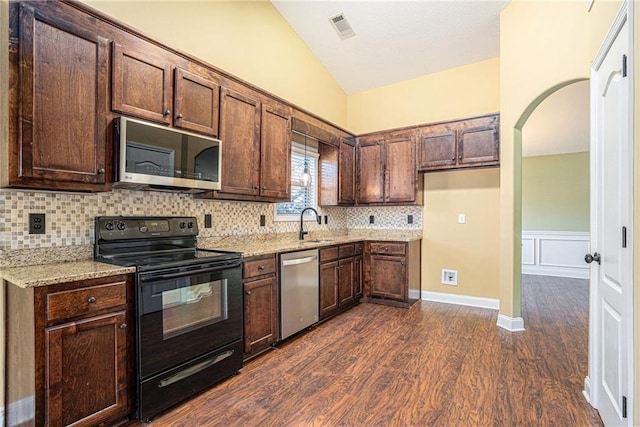 kitchen featuring lofted ceiling, dark wood-type flooring, sink, light stone countertops, and appliances with stainless steel finishes