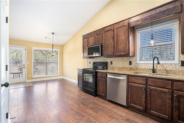 kitchen with light stone countertops, sink, decorative light fixtures, vaulted ceiling, and appliances with stainless steel finishes