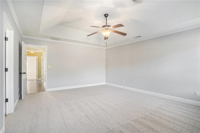 carpeted empty room with a tray ceiling, crown molding, and ceiling fan