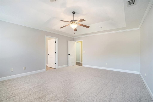 carpeted spare room featuring ceiling fan, a raised ceiling, and crown molding