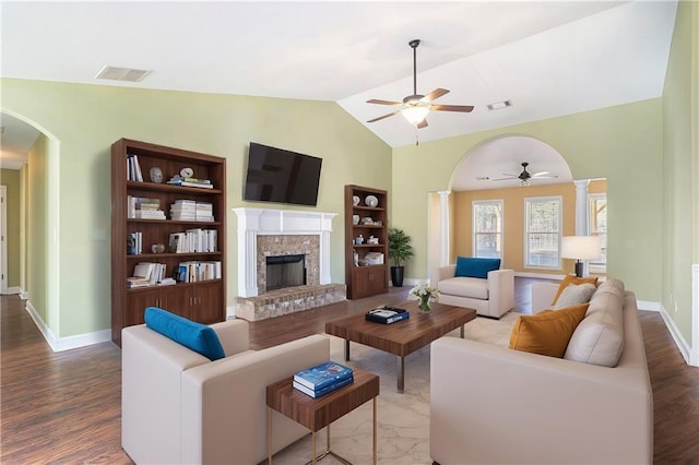 living room featuring hardwood / wood-style floors, vaulted ceiling, a brick fireplace, ceiling fan, and ornate columns