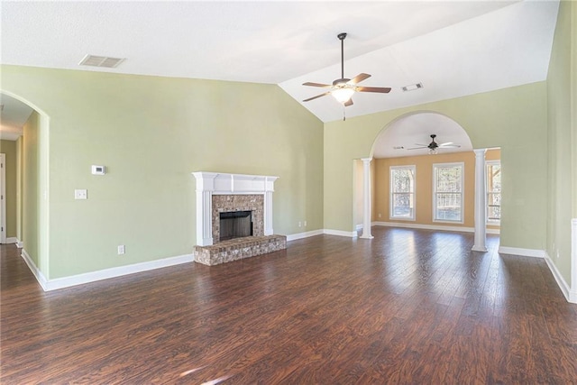 unfurnished living room featuring dark wood-type flooring, vaulted ceiling, ceiling fan, ornate columns, and a fireplace