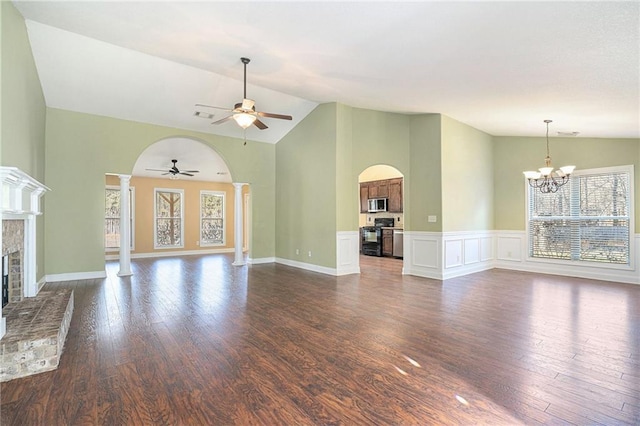 unfurnished living room with ceiling fan with notable chandelier, dark hardwood / wood-style flooring, decorative columns, and vaulted ceiling