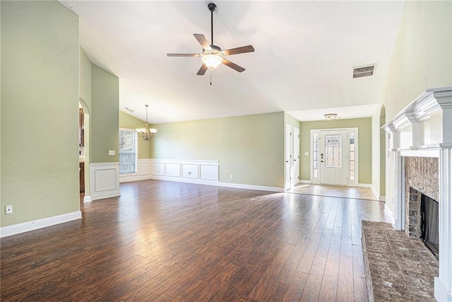 unfurnished living room with ceiling fan with notable chandelier, dark wood-type flooring, vaulted ceiling, and a brick fireplace