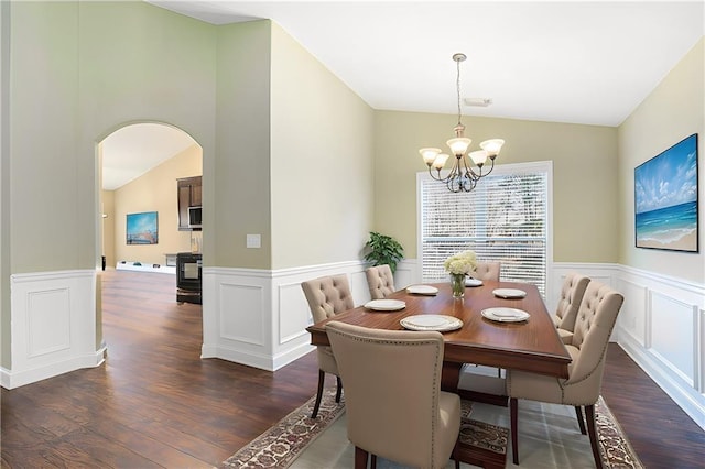 dining area with dark wood-type flooring, lofted ceiling, and an inviting chandelier