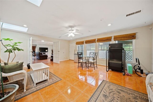 tiled living room with ceiling fan, a healthy amount of sunlight, and a skylight