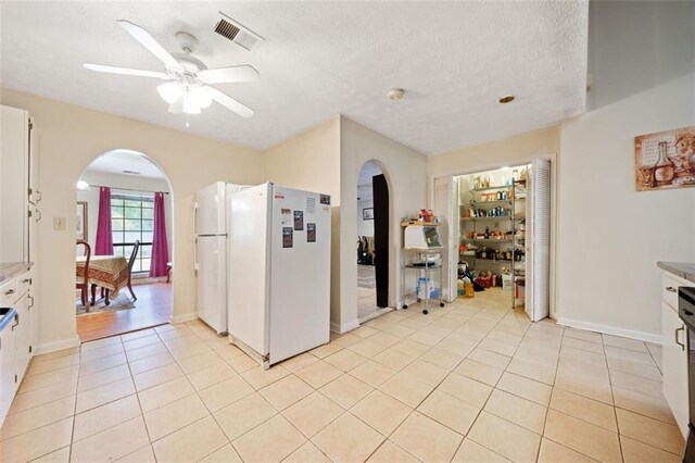 kitchen featuring white cabinetry, ceiling fan, light tile patterned floors, and white refrigerator