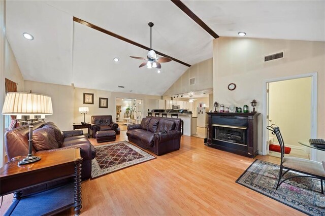 living room with ceiling fan, light hardwood / wood-style flooring, and high vaulted ceiling