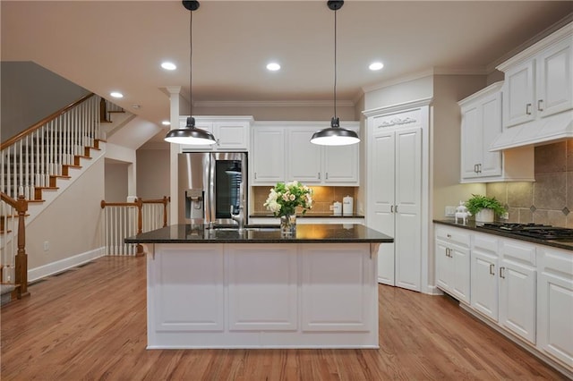 kitchen with gas cooktop, stainless steel fridge, decorative light fixtures, and an island with sink