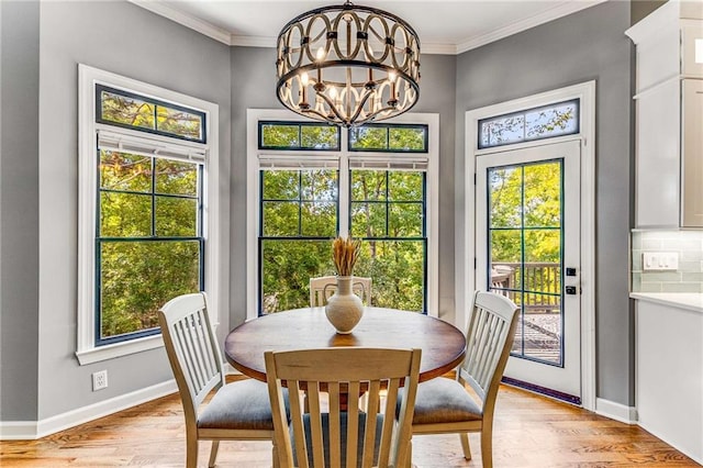 dining area featuring light wood-style floors, baseboards, ornamental molding, and a notable chandelier