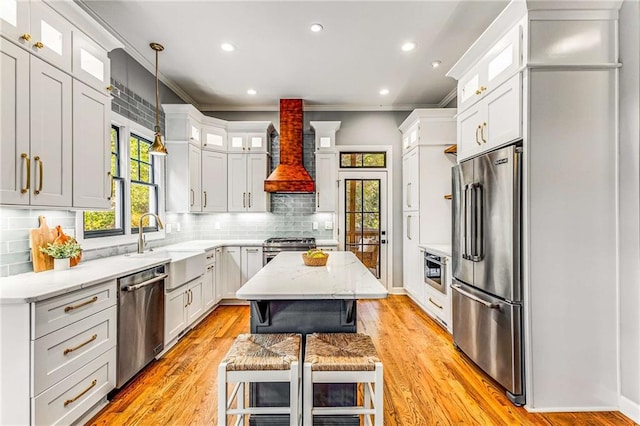 kitchen with stainless steel appliances, a kitchen island, decorative backsplash, wall chimney exhaust hood, and crown molding