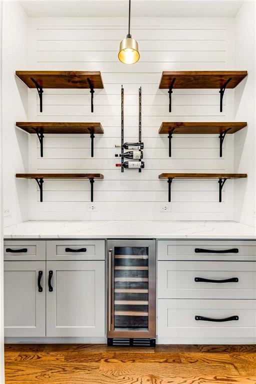 bar with light wood-type flooring and beverage cooler