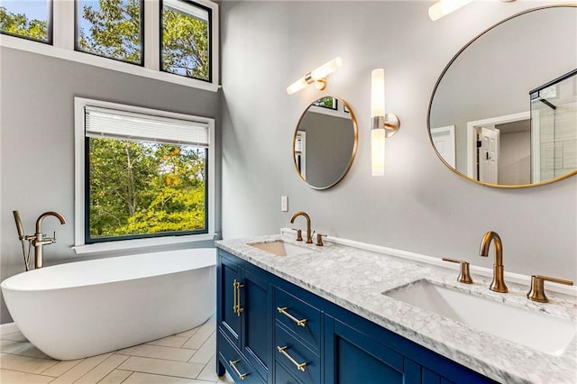 full bathroom featuring double vanity, a freestanding bath, and a sink