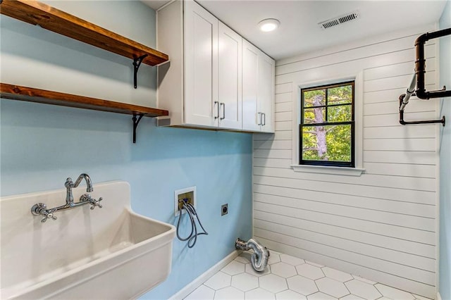 laundry room with hookup for a washing machine, wood walls, visible vents, cabinet space, and electric dryer hookup