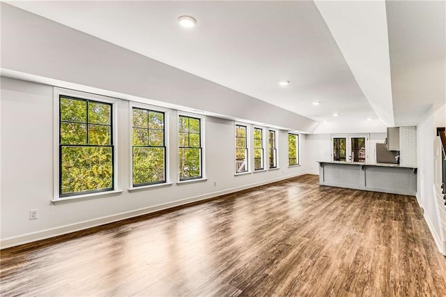 unfurnished living room featuring lofted ceiling, baseboards, wood finished floors, and recessed lighting