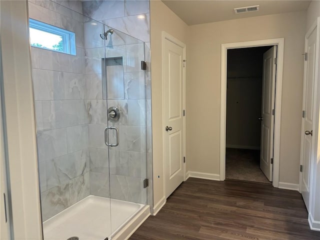 bathroom featuring baseboards, wood finished floors, a stall shower, visible vents, and a closet