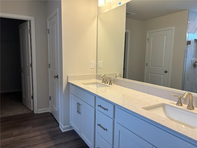 bathroom with double vanity, a sink, wood finished floors, and visible vents