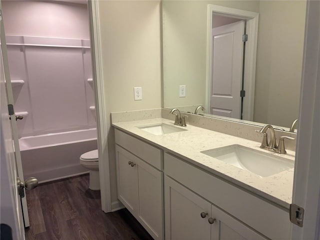 full bathroom featuring double vanity, toilet, a sink, and wood finished floors
