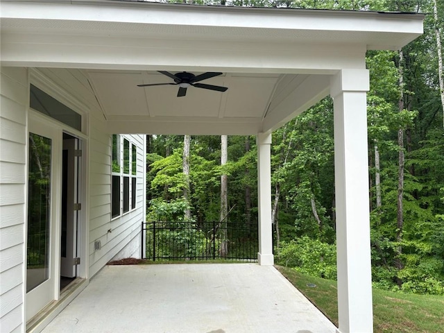 view of patio featuring fence, a ceiling fan, and a forest view